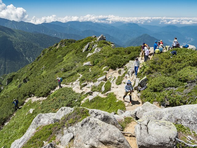 登山者で賑わう山頂付近と西側の眺め